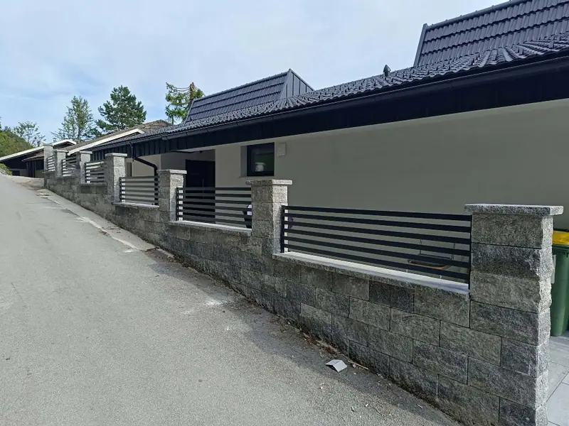 Ograja s horizontalnimi polnili med kamnitimi stebri ob cesti